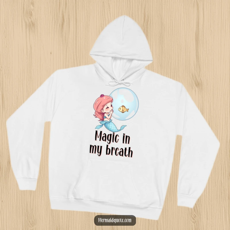 Funny hoodie showcasing a mermaid blowing a shimmering bubble that holds a tiny fish, a design full of magic and charm.