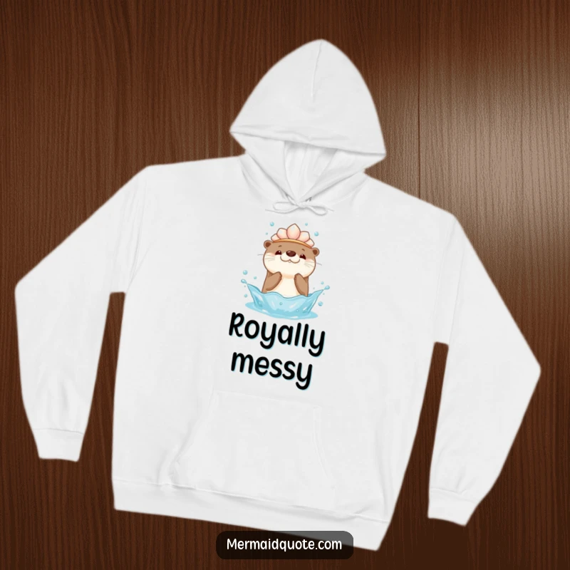 Funny hoodie design of a kawaii otter wearing a seashell crown, playfully splashing water upwards, offering warmth and adorable humor.